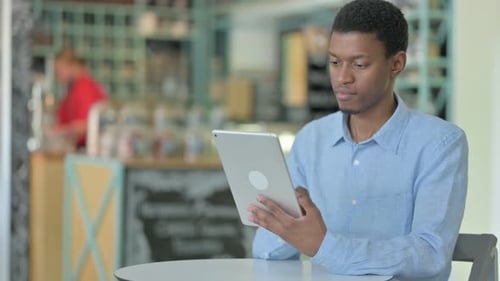 Professional Young African Man Using Tablet in Cafe