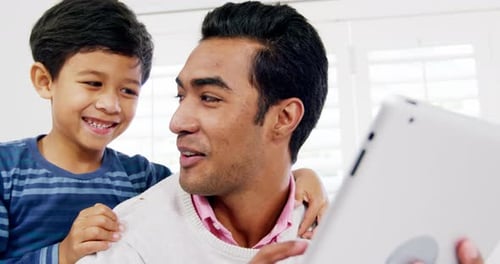 Smiling Father and Son Using Tablet at Home