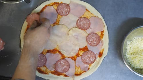 Preparing Pizza with Salami and Ham overhead shot