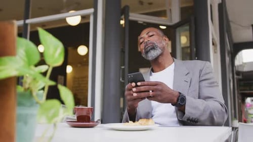 Senior African American Man Using Smartphone at Cafe