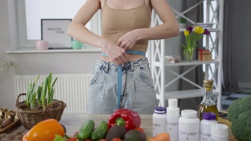 Slim Woman Measures Waist with Tape Measure
