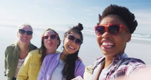 Happy group of diverse female friends having fun, taking selfie with smartphone at the beach
