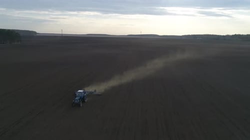 Tractor plow in a huge field. Spring, evening