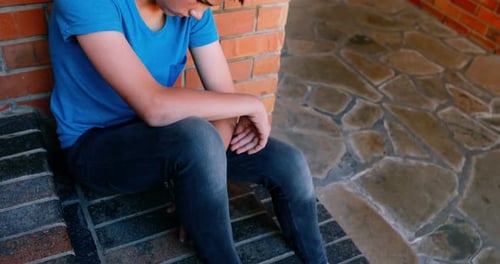 Sad schoolboy sitting alone on staircase