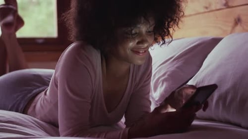 Woman Lying on Bed Using Mobile Phone