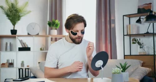 Man Applies Eye Patches in Modern Home Setting