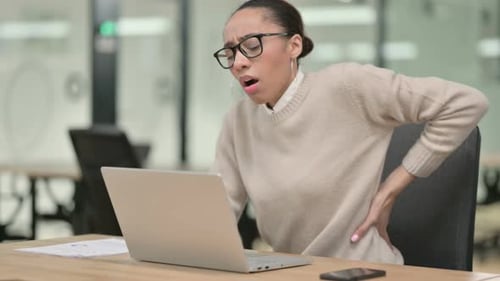 Young Woman Working at Laptop Experiencing Back Pain