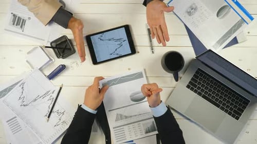 Top View Male Hands of Two Business Partners Checking Graphs and Discussing Financial Reports