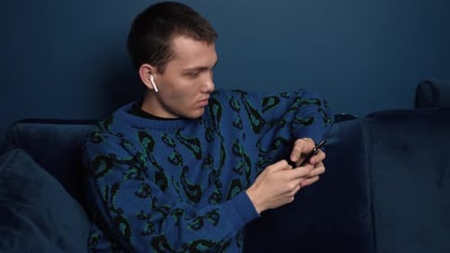 Young Man Relaxing Indoors with Mobile Phone