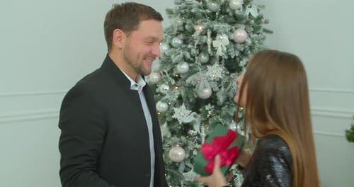 Close-up Young Woman Receiving a Holiday Present From Her Husband. Pretty Girl Hugging with