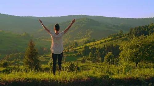 Woman Stretches in Rural Mountain Meadow at Sunrise