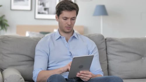 Man Reacts Positively to Tablet News at Home