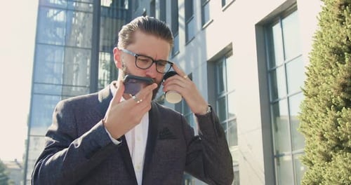 Bearded Man Uses Speakerphone Outside Modern Building