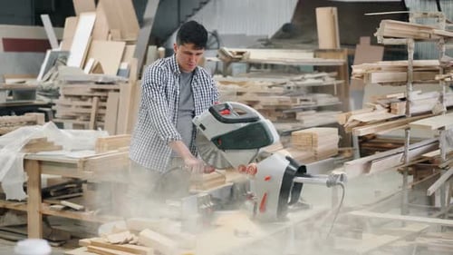 Carpenter Cleaning Circular Saw From Sawdust Working in Workshop Indoors
