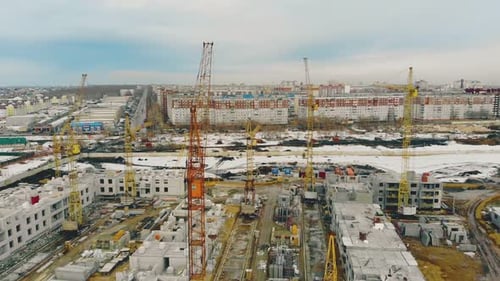 Construcción en curso de edificios con grúas contra la ciudad