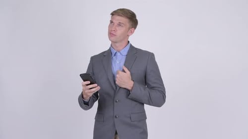 Thoughtful Young Businessman Using Smartphone in Studio