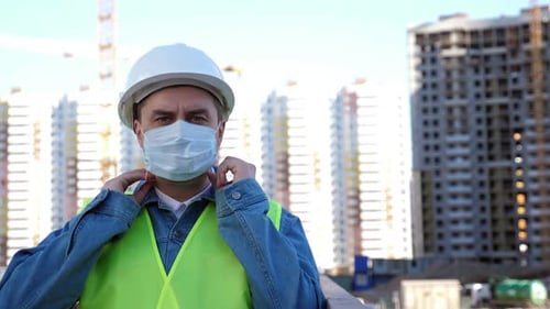 Construction Worker Puts On Mask Outside at Worksite