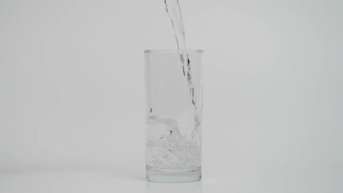 Cámara lenta de verter agua en vidrio 1000 fps sobre fondo blanco