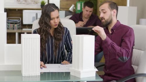 Architects Discussing Building Models in Office Setting
