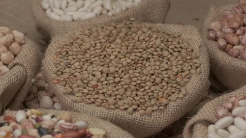Dry lentils legumes falling on jute bowl. Mediterranean diet, vegan vegetarian ingredient healthy pr