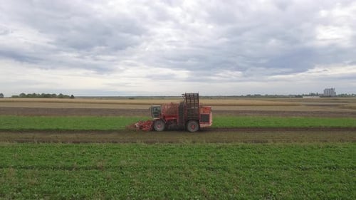 Harvester Machine Working on Field Under Cloudy Sky