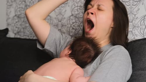 Tired Woman Holding Sleeping Baby Indoors