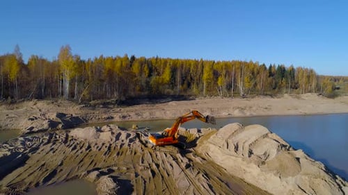 Orange Excavator Digging in a Sandy Rural Landscape