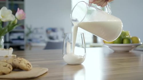 Milk is Poured into Glass on Bright Kitchen Table