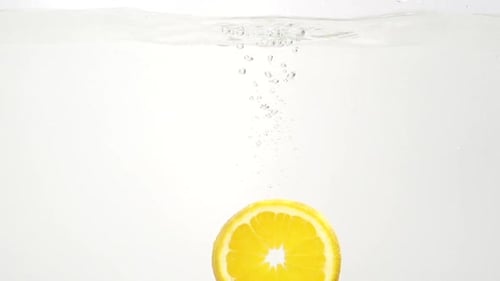 Orange Slice Plunging Into Water With Bubbles