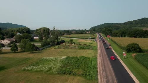 Drohnenblick über Landstraßenbaubildschirm mit wechselndem Verkehr und landwirtschaftlichen Feldern.
