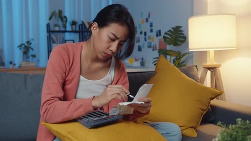 Lady feel stress worried with bill and invoice credit card calculating money on sofa at home night