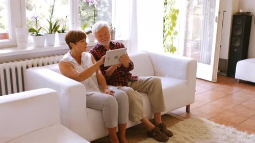 Senior Couple Relaxing on Couch Using Tablet Device