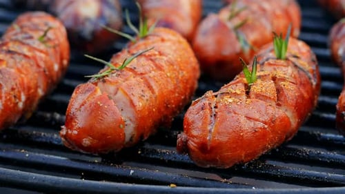 Tasty and red sausage on grill with spices and herbs in summer