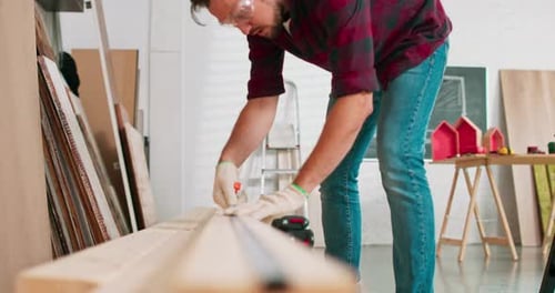 Carpenter Measures Wood in Bright Workshop