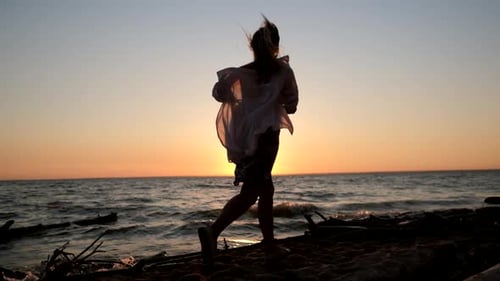 Woman Runs Along Sandy Beach at Sunset