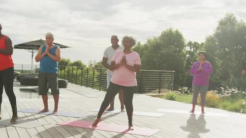 Senior diverse people practicing yoga in garden at retirement home