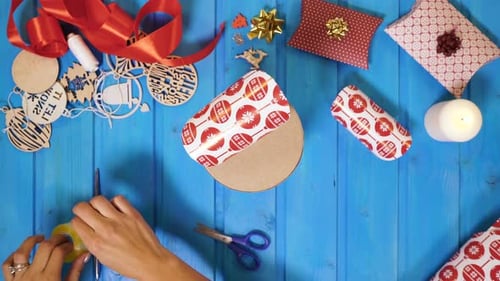 Wrapping Christmas Gift with Decorative Paper on Tabletop
