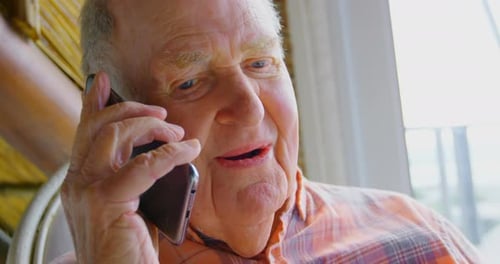 Close-up of Caucasian senior man talking on mobile phone in a comfortable home 4k