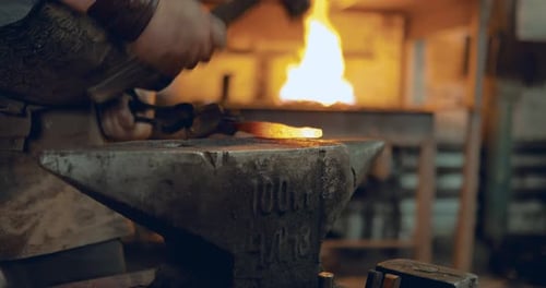 Craftsman Hammering Red Hot Metal in Workshop