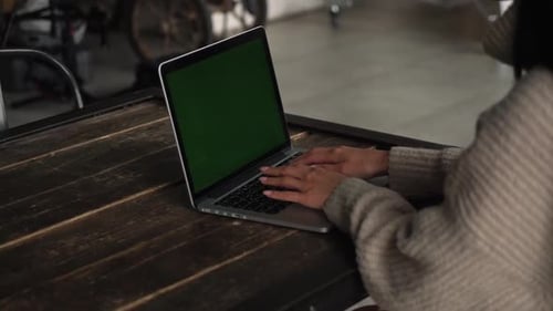 An Attractive Woman Working on Her Computer on a Couch, Slow Motion. Asian Girl Sits Behind the