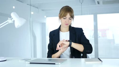 Junge Frau nutzt Smartwatch bei der Arbeit im Büro