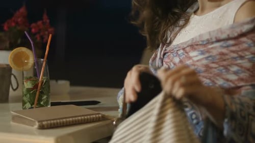 Young Woman Using Phone at Outdoor Table at Night
