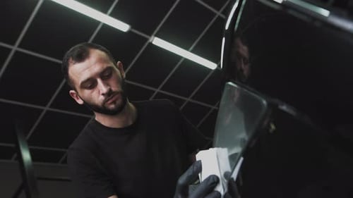 Detailer Polishing Black Car in Garage