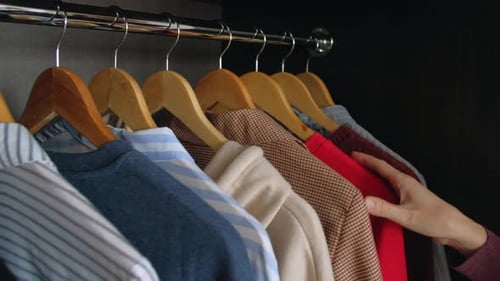 Hand Selects Shirt from Organized Closet Wardrobe