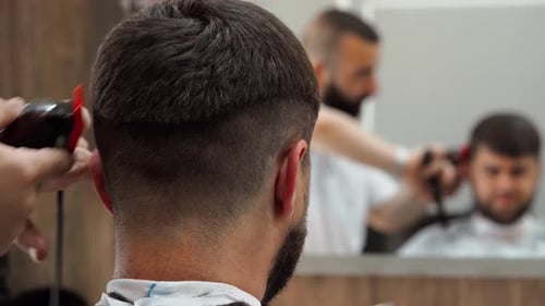 Barbier macht einen Haarschnitt für männlichen Kunden im Barbershop Nahaufnahme