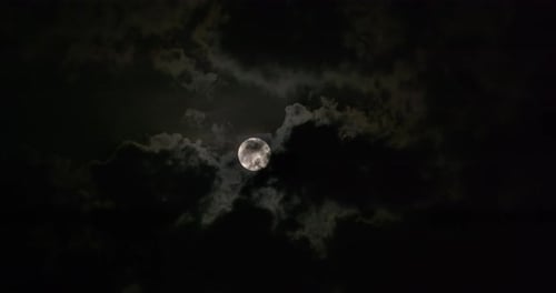 Full Moon Shines Through Dark Clouds in the Night