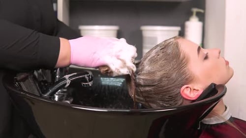 Hair Stylist Washing Woman's Hair in Salon