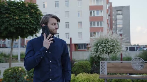 Young Man Talking on Phone in City Park