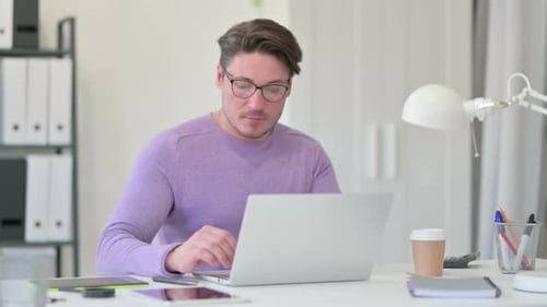 Man Works at Laptop in Bright Home Office