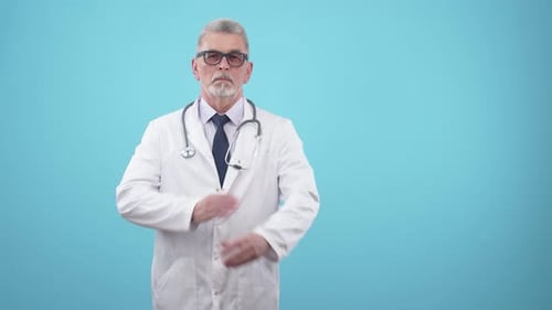 Serious Senior Man Doctor in Medical Form Confidently Crosses Hands on Chest Standing in the Studio
